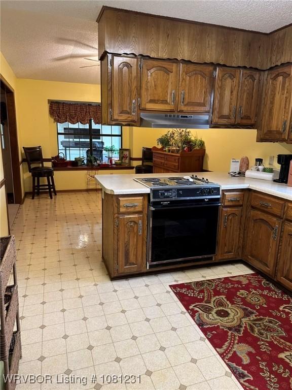 5108 S 94th St, Fort Smith, AR 72903 - kitchen featuring black gas range oven, under cabinet range hood, light countertops, light floors, and a textured ceiling