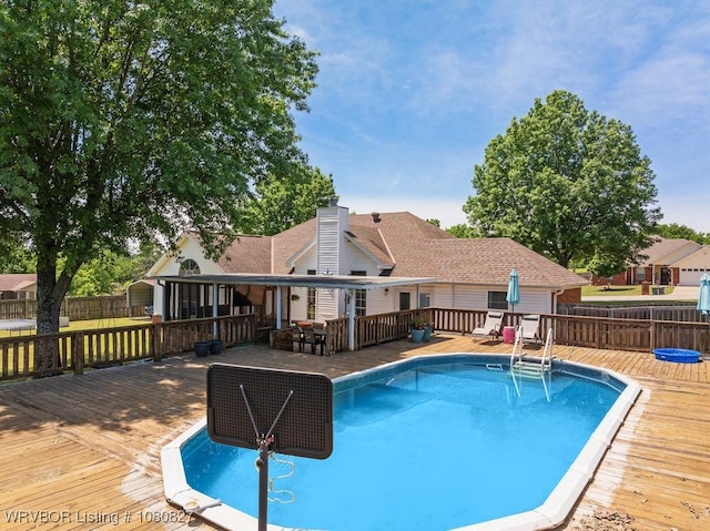 view of swimming pool featuring a deck and fence