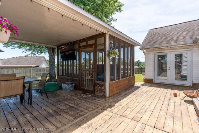 wooden deck featuring a sunroom, french doors, outdoor dining space, and fence