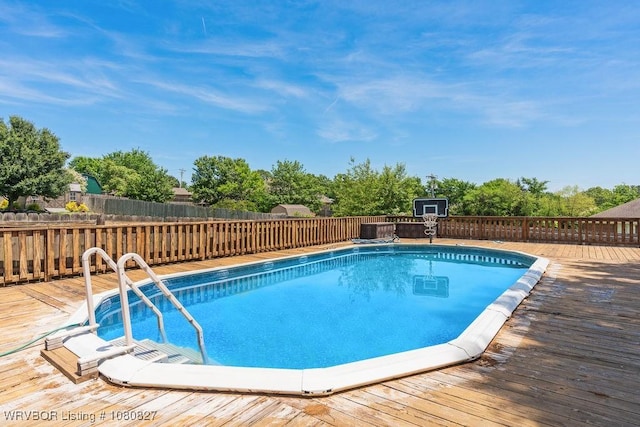 view of pool featuring a deck, a fenced backyard, and central AC unit
