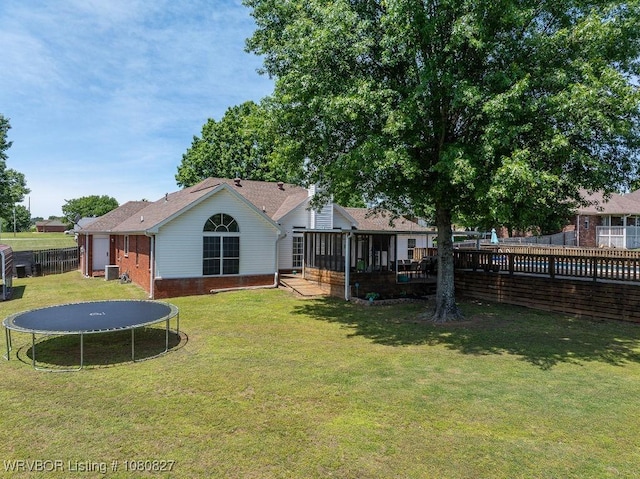 back of property featuring a trampoline, brick siding, central AC unit, and a sunroom