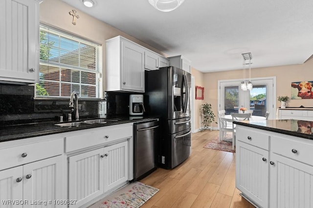 kitchen featuring stainless steel appliances, a sink, backsplash, white cabinetry, and light wood-style floors