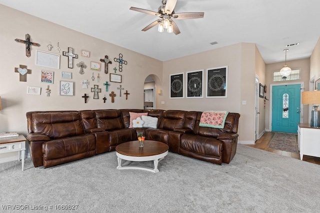 living area featuring arched walkways, carpet floors, ceiling fan, and baseboards