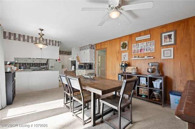 dining area featuring ceiling fan and light carpet