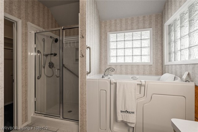 7004 Millennium Dr, Fort Smith, AR 72916 - full bath featuring wallpapered walls, plenty of natural light, a stall shower, a garden tub, and washer / clothes dryer