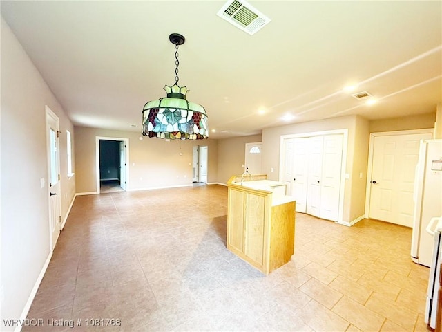 900 S Mattox Ln, Sallisaw, OK 74955 - kitchen with freestanding refrigerator, open floor plan, light countertops, a kitchen island with sink, and decorative light fixtures