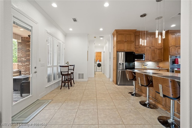 38 Jeffrey Way, Fort Smith, AR 72903 - kitchen featuring appliances with stainless steel finishes, tasteful backsplash, washing machine and clothes dryer, recessed lighting, and a kitchen breakfast bar