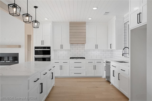 kitchen featuring pendant lighting, white cabinets, sink, light stone countertops, and light wood-type flooring