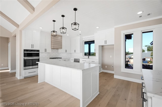 kitchen featuring white cabinets, a center island, light stone counters, and appliances with stainless steel finishes