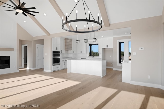 kitchen featuring pendant lighting, a center island, white cabinets, tasteful backsplash, and a large fireplace