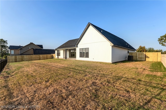 back of property featuring a lawn and central AC