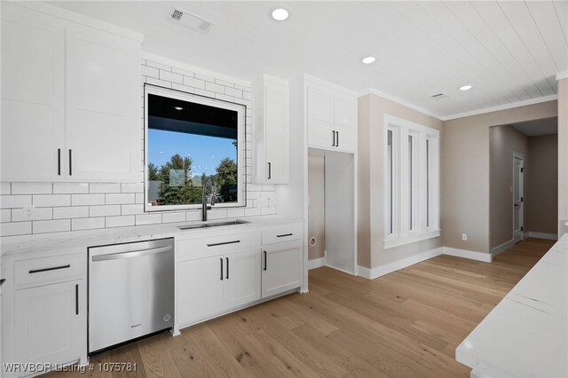 kitchen featuring stainless steel dishwasher, white cabinets, light stone countertops, and sink