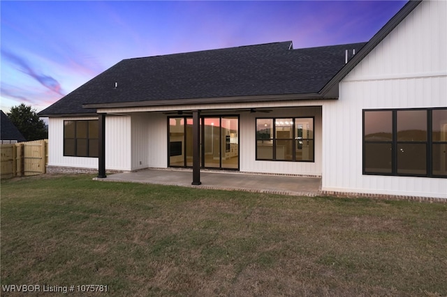 back house at dusk featuring a yard and a patio