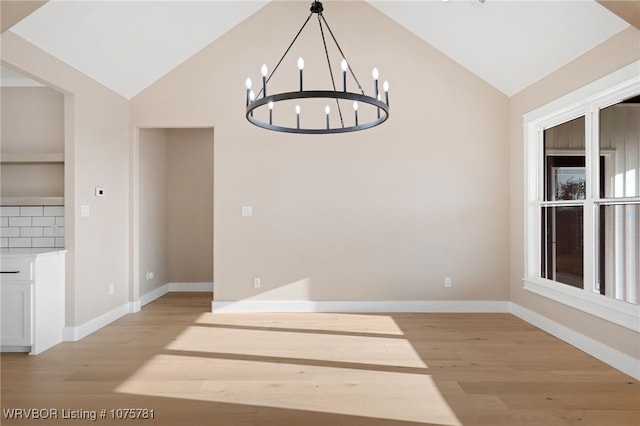 unfurnished dining area featuring a notable chandelier, light hardwood / wood-style floors, and lofted ceiling