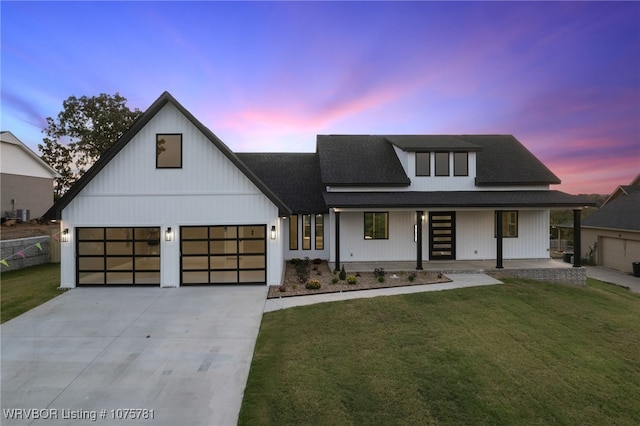 modern farmhouse style home featuring a garage, covered porch, and a yard