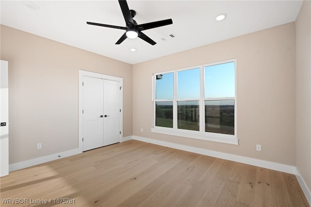 unfurnished bedroom featuring ceiling fan, a closet, and light hardwood / wood-style flooring