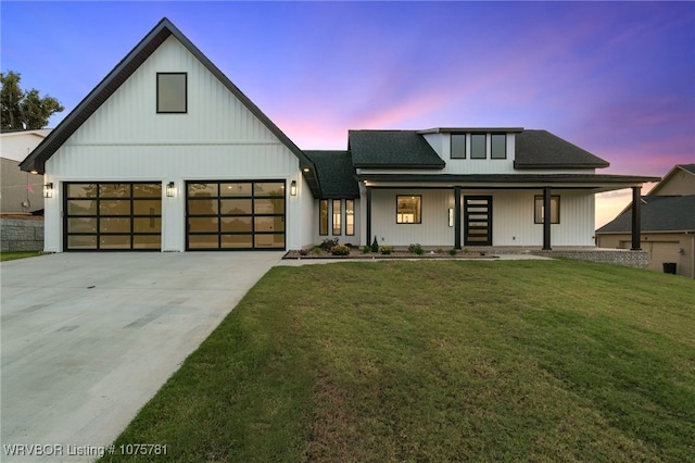 modern farmhouse featuring covered porch, a yard, and a garage