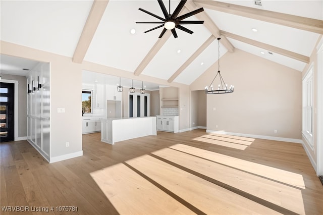 unfurnished living room featuring beam ceiling, high vaulted ceiling, ceiling fan with notable chandelier, and light wood-type flooring