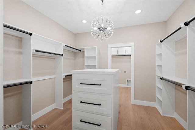 walk in closet with light hardwood / wood-style floors and a notable chandelier