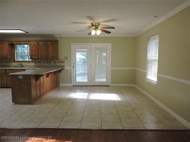 2211 Breckenridge Ter, Greenwood, AR 72936 - kitchen with light tile patterned flooring, a kitchen bar, a peninsula, backsplash, and ceiling fan