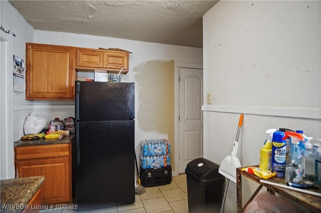 kitchen featuring black refrigerator, light tile patterned floors, and a textured ceiling