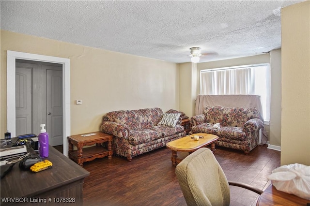 living room featuring ceiling fan, dark hardwood / wood-style flooring, and a textured ceiling