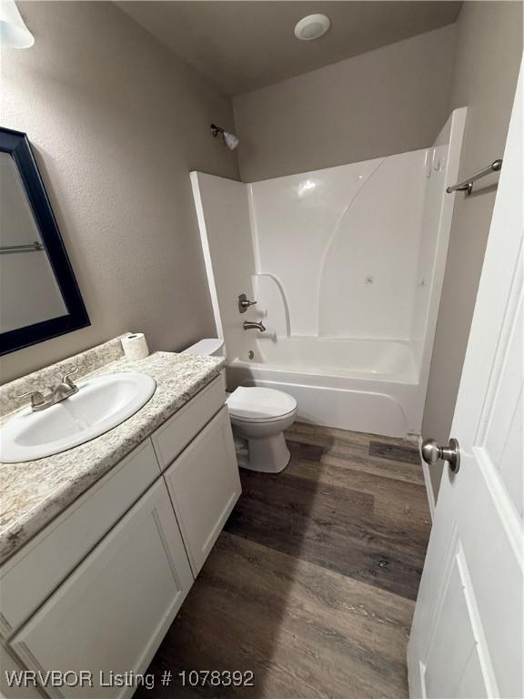 full bathroom featuring toilet, vanity, wood-type flooring, and bathing tub / shower combination