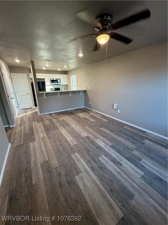 unfurnished living room with a textured ceiling, ceiling fan, and dark hardwood / wood-style flooring