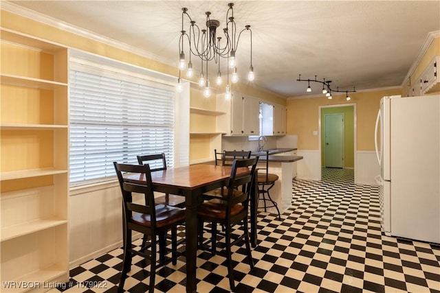 dining space featuring ornamental molding, sink, and a chandelier