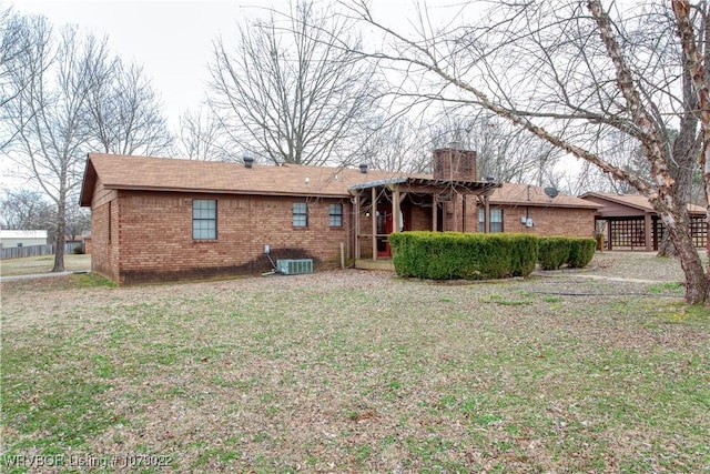 rear view of house featuring central AC and a lawn