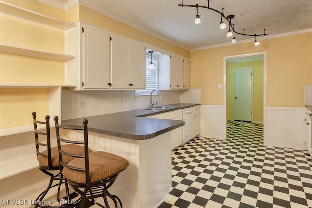 kitchen with dishwasher, sink, white cabinets, crown molding, and track lighting