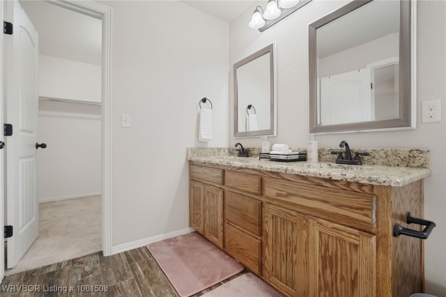 106 Stone Dr, Roland, OK 74954 - bathroom with double vanity, a walk in closet, and wood finished floors