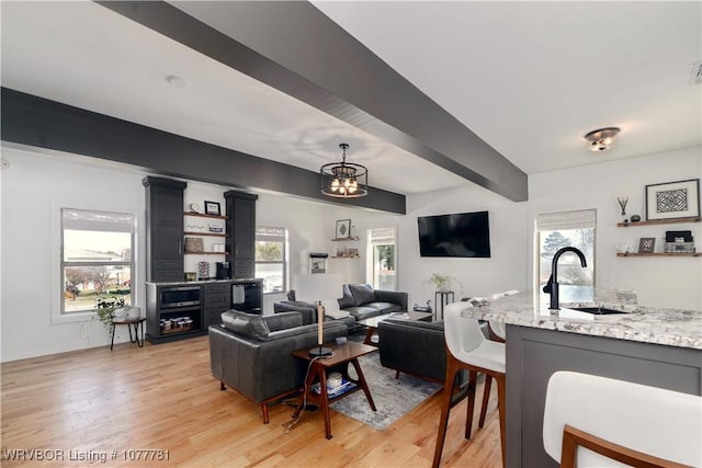 living room with sink, a notable chandelier, and light hardwood / wood-style flooring