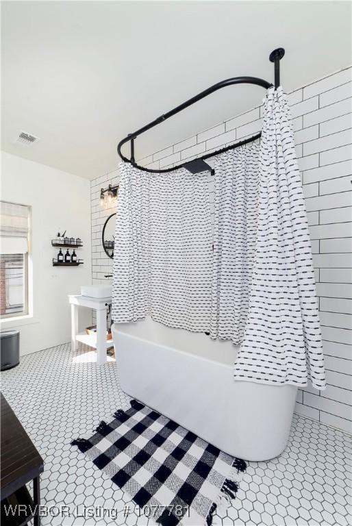 bathroom with tile patterned floors and shower / bath combo with shower curtain