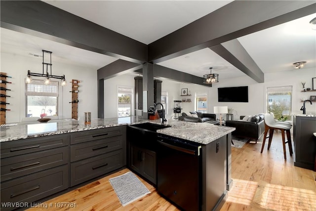 kitchen with light stone countertops, dishwasher, sink, and light wood-type flooring