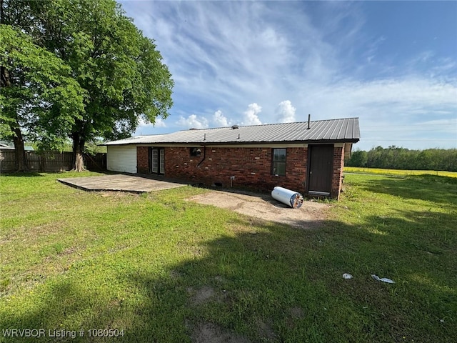 back of property with metal roof, a yard, a patio, and fence