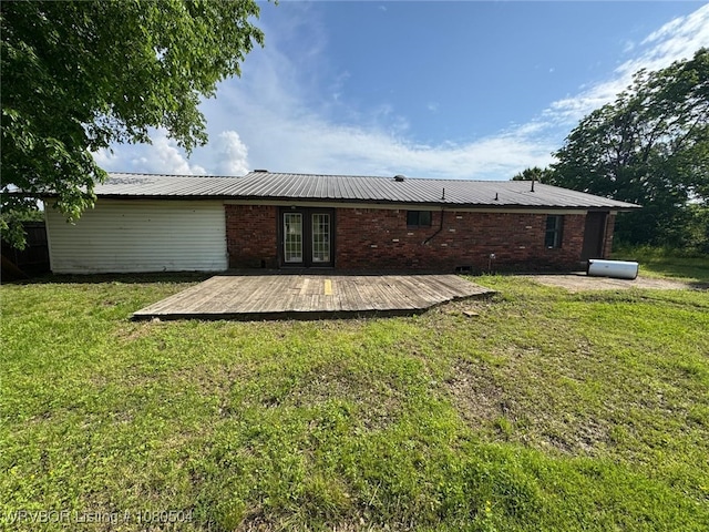 back of property with a lawn, metal roof, french doors, and a deck