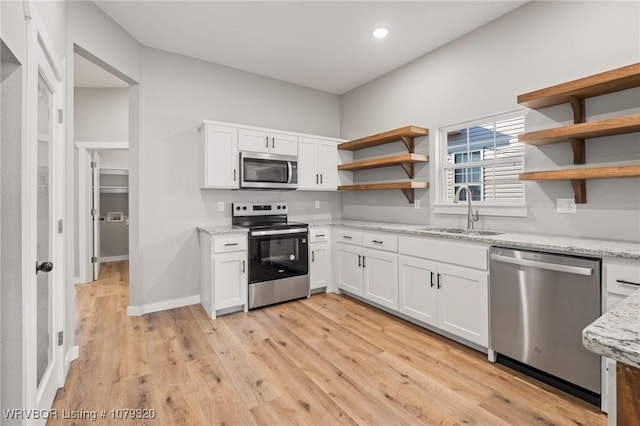 kitchen with a sink, open shelves, appliances with stainless steel finishes, and white cabinetry