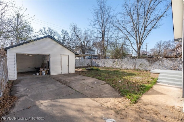 detached garage with concrete driveway and fence