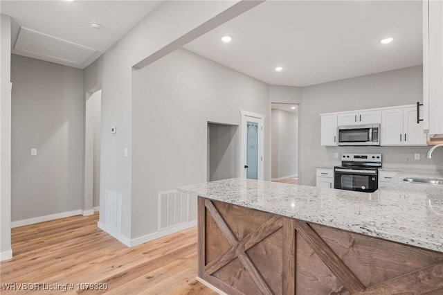 kitchen with light stone counters, visible vents, a sink, stainless steel appliances, and white cabinetry