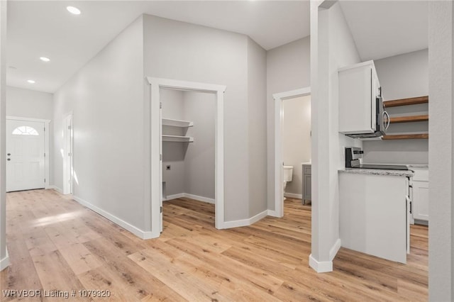 corridor featuring recessed lighting, light wood-type flooring, and baseboards