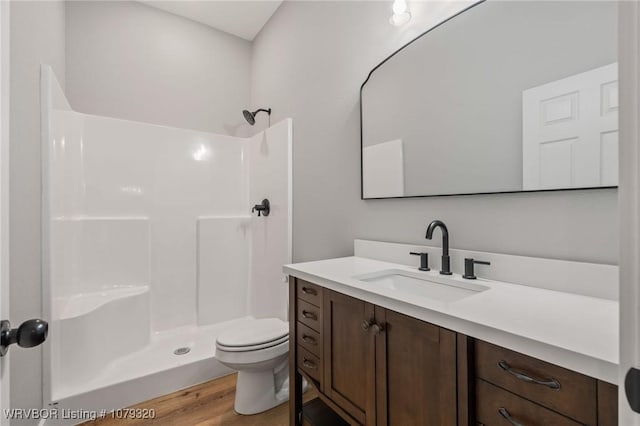 full bathroom with vanity, toilet, wood finished floors, and walk in shower