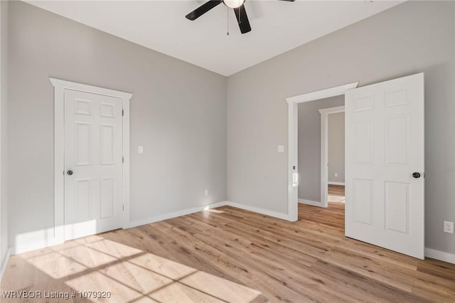 spare room featuring light wood-type flooring, baseboards, and ceiling fan