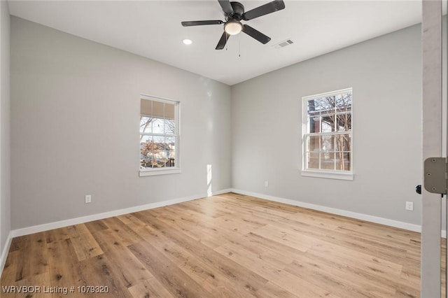 spare room with a wealth of natural light, baseboards, wood finished floors, and ceiling fan