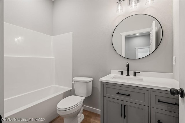 bathroom featuring toilet, wood finished floors, baseboards, bathtub / shower combination, and vanity