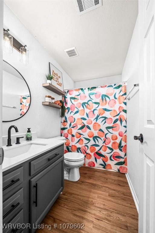 full bathroom featuring visible vents, toilet, vanity, and wood finished floors