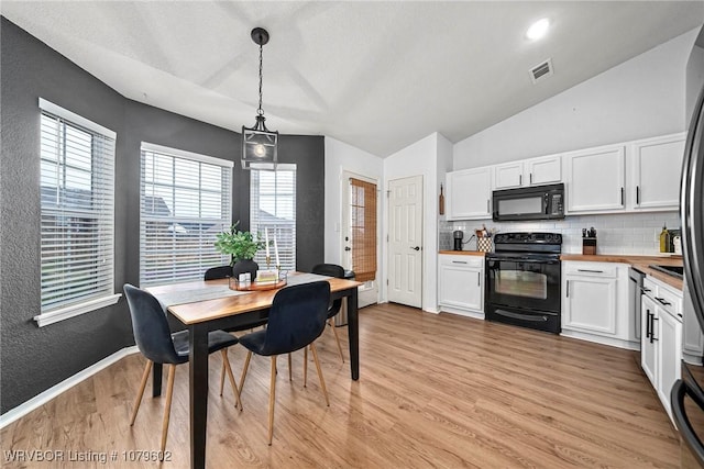 dining area featuring visible vents, baseboards, light wood-type flooring, lofted ceiling, and a textured wall