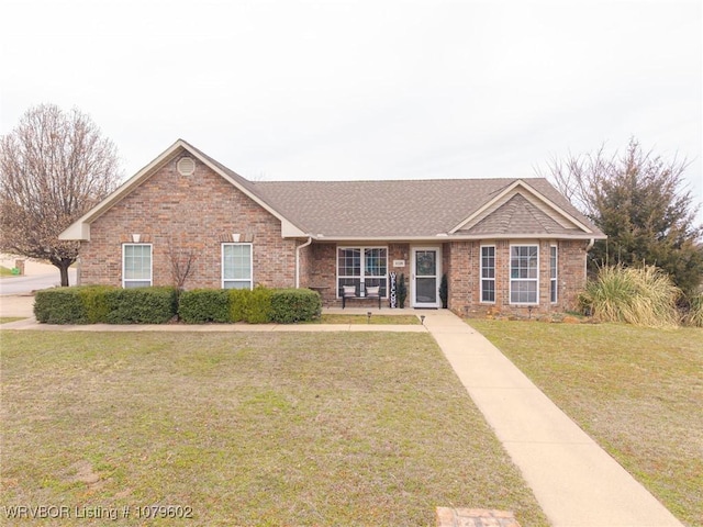 ranch-style house with a front yard, brick siding, and a shingled roof