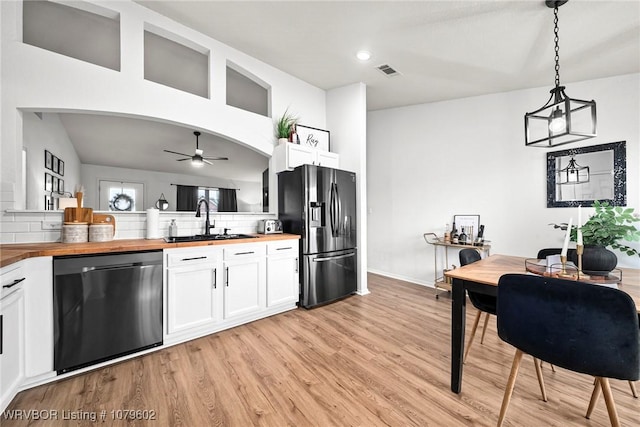 kitchen with a ceiling fan, wooden counters, a sink, dishwasher, and stainless steel fridge