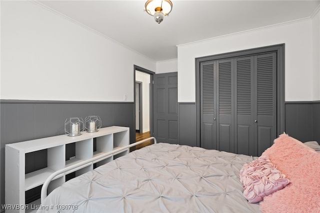 bedroom with wainscoting, crown molding, and a closet